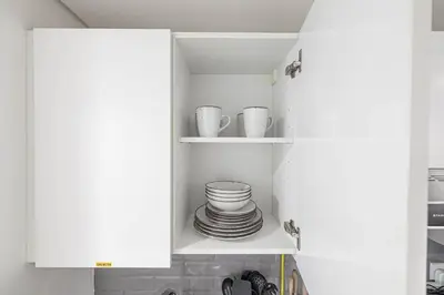 a white cupboard with plates and cups in it at Cozy Studio 7 Minutes From Dubai Mail in Dubai