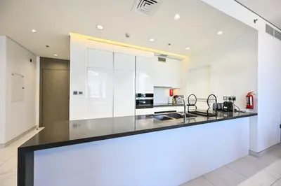 a kitchen with white walls and a black counter top at Relax in Style 2BR Huge Terrace Lagoon Access in Dubai