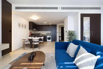 a living room with a blue couch and a kitchen at King Bed & Modern Comfort Studio in DIFC Downtown in Dubai