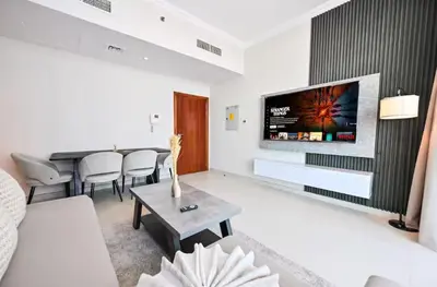 a living room with a couch and a tv on a wall at Scala Tower- Business Bay Dubai - Luxury Apartments by Canvas Holiday Homes in Dubai