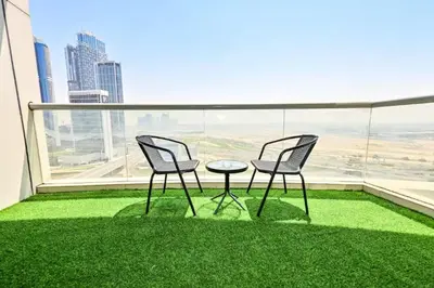 two chairs and a table on a balcony with green grass at Scala Tower- Business Bay Dubai - Luxury Apartments by Canvas Holiday Homes in Dubai