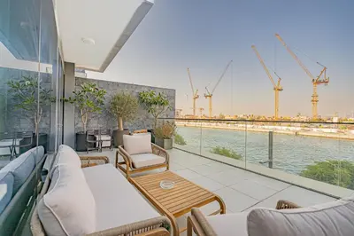 a balcony with chairs and tables and a view of a river at Escape24 Elegant 2BR with Canal view near Safa Park in Dubai