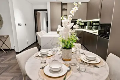a dining room with a table with plates and glasses at Chic 2BR Close to Burj Khalifa, Dubai Mall & Creek in Dubai