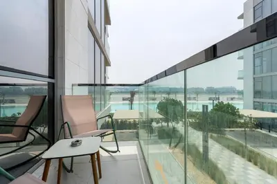 a balcony with glass windows and a table and chairs at Luxurious 1 BR in District One Beach Access in Dubai