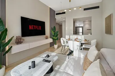 a living room with a couch and a tv on a wall at Luxury 1BR JVC Pool & Balcony by Circle Mall in Dubai