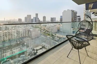 a chair on a balcony with a view of a city at Luxury 1BR JVC Pool & Balcony by Circle Mall in Dubai