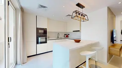 a kitchen with white cabinets and a counter and stools at Ranches 1 Upgraded Three Bedroom Villa in Dubai