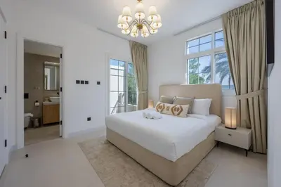 a white bedroom with a large bed and a chandelier at Ranches 1 Upgraded Three Bedroom Villa in Dubai