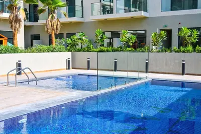 a swimming pool in front of a building at Modern Studio with Balcony and Pool Access - Holiday Boulevard in Dubai