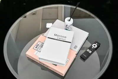a glass table with a bottle of mascara and a remote control at Modern Studio with Balcony and Pool Access - Holiday Boulevard in Dubai