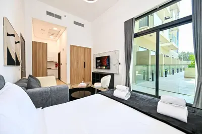 a bedroom with a bed and a living room at Modern Studio with Balcony and Pool Access - Holiday Boulevard in Dubai