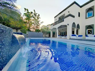 a swimming pool with a waterfall in front of a house at Signature 7-bedroom Villa Marina in Dubai