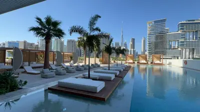 a pool with lounge chairs and palm trees on a building at THE UPSIDE Downtown Dubai in Dubai