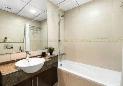 a bathroom with a white sink and a bath tub at Bay Central Modern Studio in Dubai