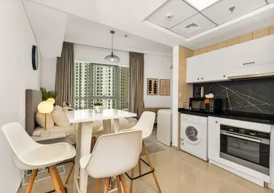 a kitchen and living room with a table and chairs at Bay Central Modern Studio in Dubai
