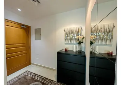 a room with a dresser with a vase of flowers on it at Luxe Vista - Top Location Dubai Marina 1BR - Metro and Beach Access in Dubai