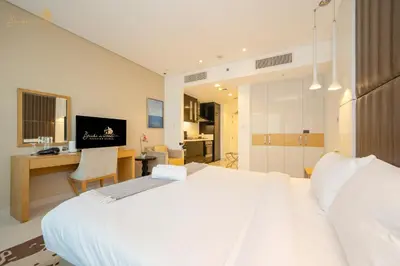 a bedroom with a large white bed and a desk at Cozy Canal View Studio in Dubai