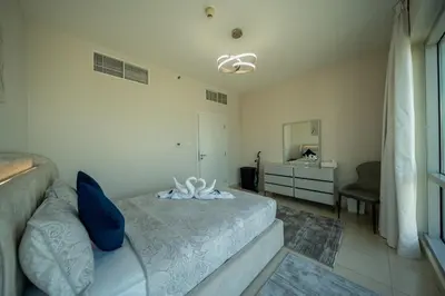 a bedroom with a bed with blue pillows and a mirror at Homes & Beyond l 2BR in the Heart of Dubai Marina in Dubai