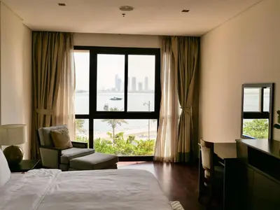 a hotel room with a bed and a chair and a window at Oceanfront 2BR Apartment with Perfect Views in Dubai