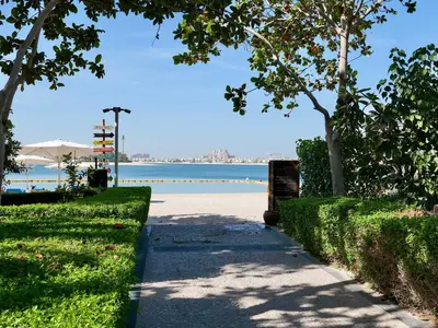 a walking path next to a beach with a body of water at Oceanfront 2BR Apartment with Perfect Views in Dubai