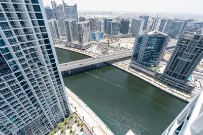 a bridge over a river in a city with tall buildings at Luxury Canal-View Stay in Damac Privee in Dubai