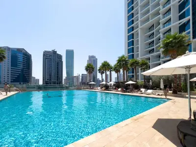 a large swimming pool with a city skyline in the background at Luxury Canal-View Stay in Damac Privee in Dubai