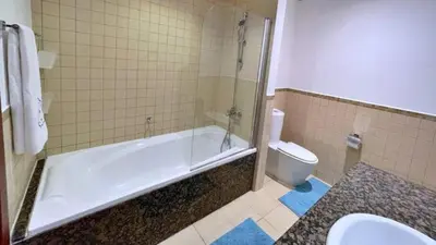 a bathroom with a bath tub and a toilet at Devine Homes JBR Hostel in Dubai