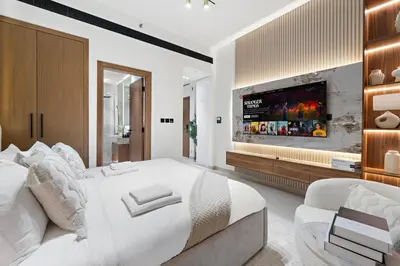 a white bedroom with a large bed and a tv at Chic Studio with Balcony and Gym at JVC in Dubai