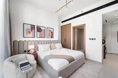 a bedroom with a large bed and a chair at Chic Studio with Balcony and Gym at JVC in Dubai