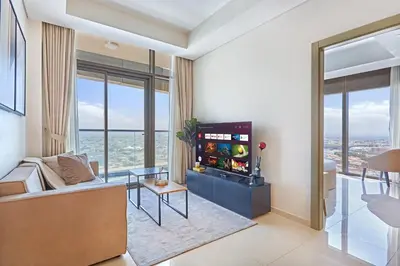a living room with a couch and a tv and windows at Aykon City 2BR Luxury Stay Close to Downtown in Dubai