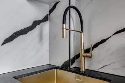 a kitchen sink with a brass faucet on a counter at Luxury Studio with Jacuzzi & Canal Views in Dubai