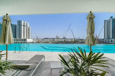 a swimming pool with two umbrellas and a city at Luxury Studio with Jacuzzi & Canal Views in Dubai
