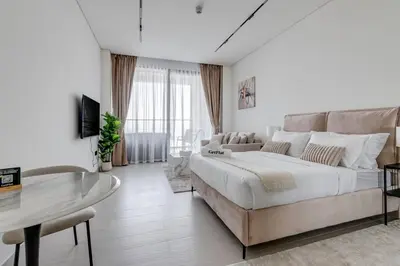 a white bedroom with a large bed and a couch at Luxury Studio with Jacuzzi & Canal Views in Dubai