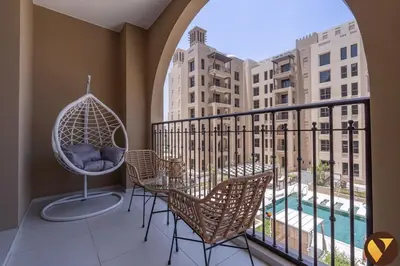 a balcony with chairs and a swing and a pool at Vogue Madinat Jumeirah Living Jadeel near Burj AlArab, One-Bedroom Apartment with Large Balcony and Pool View, Access to All Amenities in Dubai