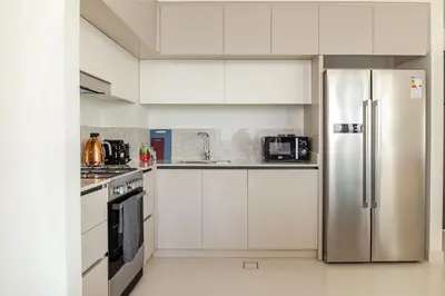 a kitchen with white cabinets and a stainless steel refrigerator at 2BR-Beach Access - Stunning Marina&Palm View in Dubai