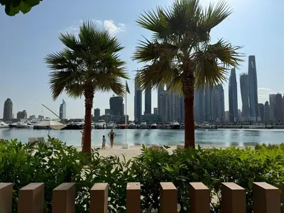 two palm trees on a beach in front of a city at 2BR-Beach Access - Stunning Marina&Palm View in Dubai