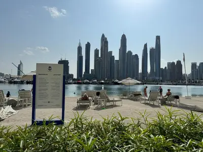 a sign with people sitting in chairs in front of a city at 2BR-Beach Access - Stunning Marina&Palm View in Dubai