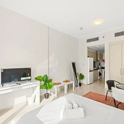 a white living room with a bed and a tv at Damac Hills Carson A Monthly Stay - Pay 28, Stay 30 in Dubai