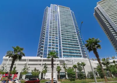 a tall building with palm trees in front of it at Damac Hills Carson A Monthly Stay - Pay 28, Stay 30 in Dubai