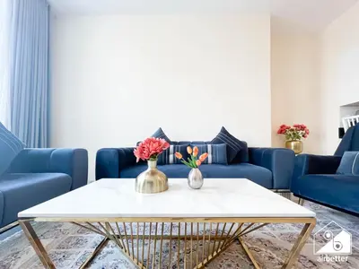 a living room with a table and blue couches at Business Bay 2BR in Amna Tower & Canal Views in Dubai