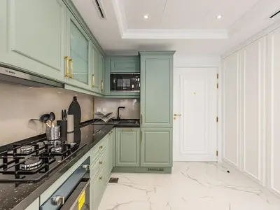 a kitchen with green cabinets and a stove at Arjan 1BR Near Miracle Garden Pool & Parking in Dubai