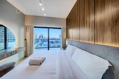 a bedroom with a large bed with a large window at Binghatti Emerald, Jumeirah Village Circle in Dubai