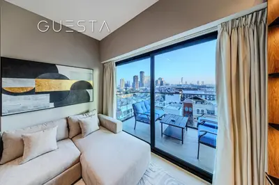 a living room with a couch and a large window at Binghatti Emerald, Jumeirah Village Circle in Dubai