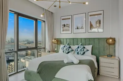 a bedroom with a large bed and large windows at Tranquil & Modern 2BR - Vida Residence Creek Beach in Dubai