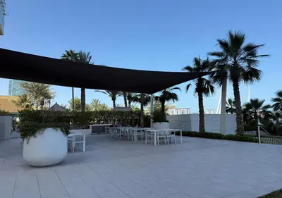a patio with white tables and a black covering at La Vie Beachside Elegance in Dubai