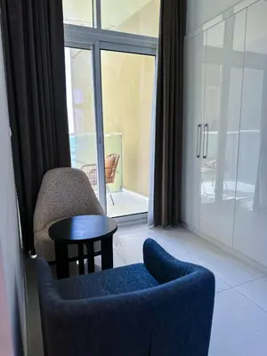 a living room with a chair and a table and a window at Stylish 2BR Retreat in JVC in Dubai