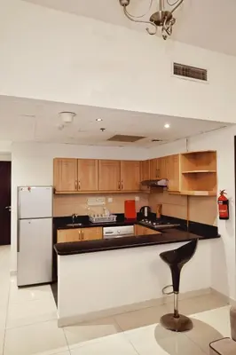a kitchen with wooden cabinets and a white refrigerator at Sport City with gym, pool, sauna in Dubai