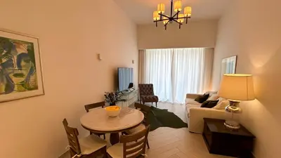 a living room with a table and a living room with a couch at Bespoke Holiday Homes - Stylish 2BR in Oxford 212 JVC in Dubai