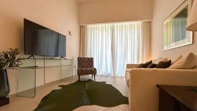 a living room with a couch and a flat screen tv at Bespoke Holiday Homes - Stylish 2BR in Oxford 212 JVC in Dubai