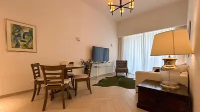 a living room with a dining table and a living room with a couch at Bespoke Holiday Homes - Stylish 2BR in Oxford 212 JVC in Dubai